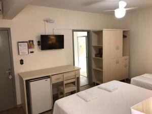 巴拉韦利亚Hotel Mirante的客房设有两张床和一张桌子,墙上配有电视。