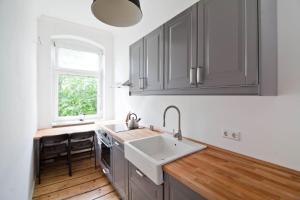 柏林Magnificent turn of century flat (legal)的厨房配有灰色橱柜、水槽和窗户。