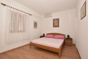 马卡尔斯卡Guest house Rose&Ana的一间卧室配有带粉红色枕头的床和窗户。