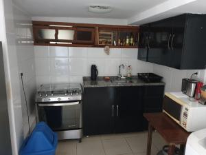 布希奥斯Lindo Apartamento em Buzios的一间小厨房,配有黑色橱柜和炉灶