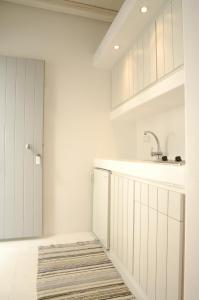 阿波罗尼亚Kapetan Tasos Suites的厨房配有白色橱柜、水槽和地毯。