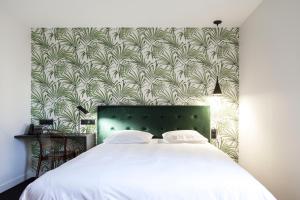 拉瓦勒Logis Hotel du Maine的一间卧室配有一张白色床和绿色床头板