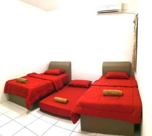 山打根Izzanial Homestay的宿舍间的两张床,配有红色床单和枕头
