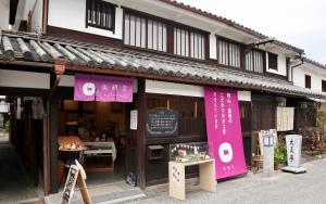 仓敷Temari Inn Yukikai的一间在大楼前方的商店,上面有粉红色的横幅