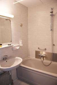 尼维莱特巴德尼维莱特巴德弗莱彻餐厅酒店的浴室设有水槽、浴缸和镜子