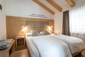 科姆梅扎杜拉Aparthotel Dolomites Living&Relax的卧室设有一张白色大床和一扇窗户。