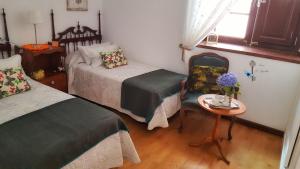 拉拉古纳Casa Le Papillon的一间卧室配有两张床、一张桌子和一把椅子