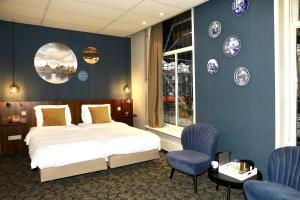 代尔夫特克普汉德尔酒店的一间卧室设有一张床,墙上挂有蓝色的墙壁和盘子