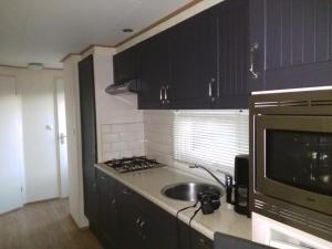 比伦Chalet Seazon R23的厨房配有黑色橱柜、水槽和微波炉