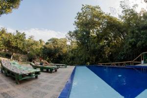 洛斯纳兰霍斯Entre Bosques Tayrona的游泳池旁边长着长凳,有两人坐在