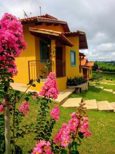 特雷斯科拉松伊斯Pousada Divina Minas的前面有粉红色花的黄色房子