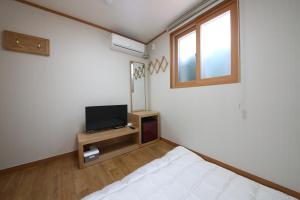 庆州Gyeongju Bee House的一间卧室设有一张床、一台电视和一个窗口。