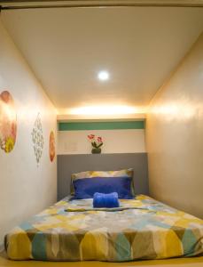 达沃市Napsule Suites的一间卧室配有一张黄色和蓝色的被子。