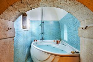 罗希姆诺Archontiko Old Town Suites的浴室设有浴缸,铺有蓝色瓷砖。