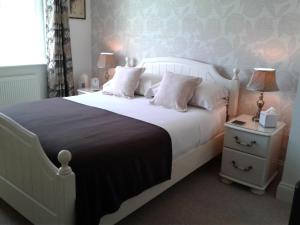 北费利比Eastdale Bed and Breakfast的一间卧室配有一张白色床、两盏灯和一个床头柜。