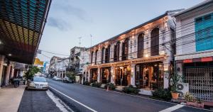 宋卡สงขลาแต่แรก แอนทีค โฮเท็ล Songkhla Tae Raek Antique Hotel的街道上拥有建筑和停车场的城市街道