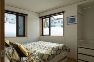 野沢Harvest House Nozawa的一间小卧室,配有床和2个窗户