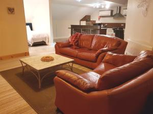基拉尼Ethan House Holiday Suites的客厅配有2张棕色皮沙发和1张桌子
