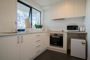 霍巴特Amazing Sea Views Luxury Guest House的厨房配有白色橱柜、水槽和微波炉