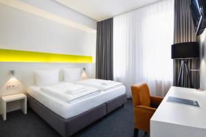 柏林柏林MK酒店的配有一张床和一把椅子的酒店客房