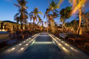 查汶Banana Fan Sea Resort的夜间有灯光和棕榈树的游泳池