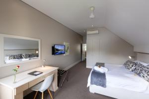 东伦敦魁瑞湖旅馆的一间卧室配有一张床、一张桌子、一张床和一张书桌
