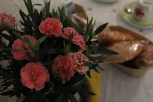 斯培西亚Punto Relax的一个带粉红色花朵的花瓶,桌子上摆放着面包