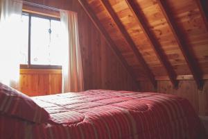 里坎雷Cabañas Puerta del Lago的一间卧室设有一张带木制天花板和窗户的床。