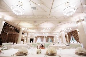 基辅科里巴别墅酒店的用餐室配有白色桌椅和吊灯。