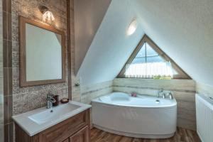 斯扎法拉瑞Domek u Kowola的一间带水槽和浴缸的浴室以及窗户。