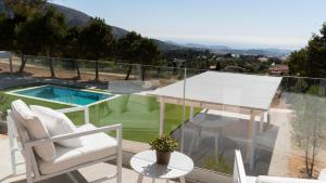 菲内斯特拉特Nature Suites Puig Campana by AR Hotels & Resorts的一个带桌椅的阳台和一个游泳池