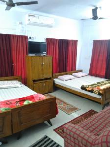 博尔普尔Chaiti Lodge - Santiniketan Bolpur的带三张床和红色窗帘的房间