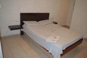 加拉加斯Hotel Tiburon的一张带白色床单和毛巾的床