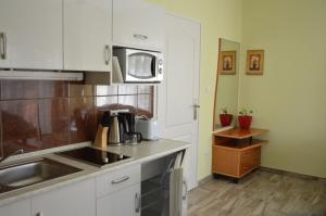 赫维兹Varga Apartman Hévíz的厨房配有白色橱柜、水槽和微波炉