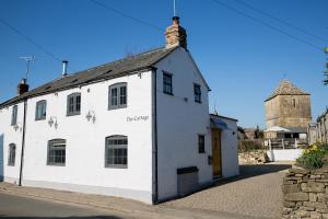 格莱顿The Cottage, Gretton (Cotswolds)的街道边的白色建筑