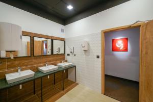 布拉迪斯拉发CHORS like a hotel - 1st World NFT Block & Art Capsule Hostel MetaCHORS的浴室设有三个水槽,墙上挂有红色的画作