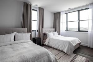 蒙特朗布朗Horizon 104 by Tremblant Prestige的白色客房的两张床,设有窗户