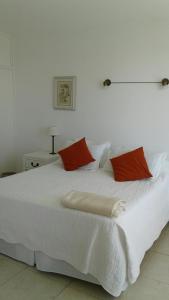 埃斯特角城Peninsula的一张带两个红色枕头的白色床