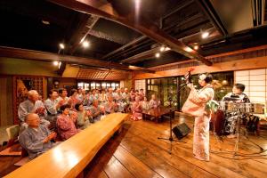 松本玉之汤酒店的一群人面前唱歌的女人
