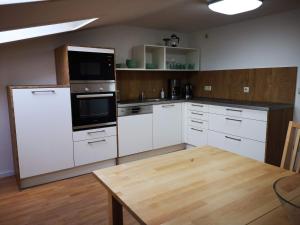 沃尔加斯特Altes Warmbad Wolgast的厨房配有白色橱柜和木桌