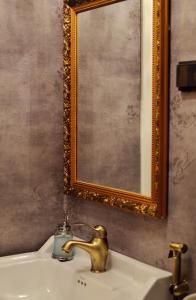 凯米Putiikkihotelli Kemi 1932的浴室水槽设有金色水龙头和镜子