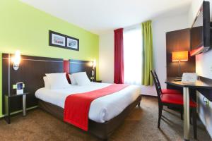 泰昂维Enzo Hotels Thionville by Kyriad Direct的酒店客房配有一张大床、一张书桌和一张四柱床。