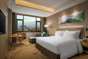 新郑郑州景瑞华美达酒店的一间酒店客房,设有一张大床和一个大窗户