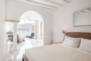 奥诺斯米科诺斯方舟酒店的一间白色卧室,配有一张床和一个拱形门廊