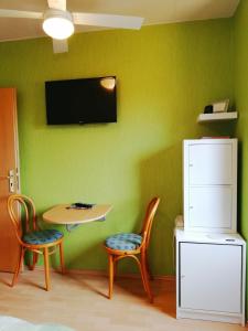 皮尔纳Privatzimmer mit Aussicht的一间设有绿色墙壁、桌子和两把椅子的客房