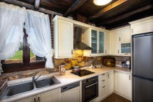 尼基季Sithonian Blue Royal Villa的厨房配有白色橱柜、水槽和冰箱。