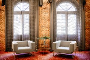 马德里珀蒂宫萨沃伊阿方索十二世高科技酒店的带大窗户的客房内的两把椅子