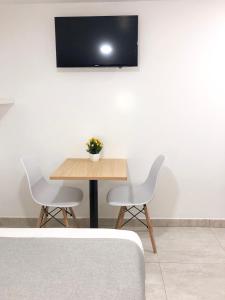 波哥大KLEINN HOTEL BOGOTÁ的一张桌子、两把椅子和墙上的电视