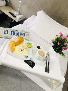 波哥大KLEINN HOTEL BOGOTÁ的早餐托盘包括鸡蛋、面包和咖啡,放在桌子上