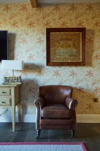EllastoneThe Duncombe Arms的客厅里一张棕色皮椅,配有壁纸
